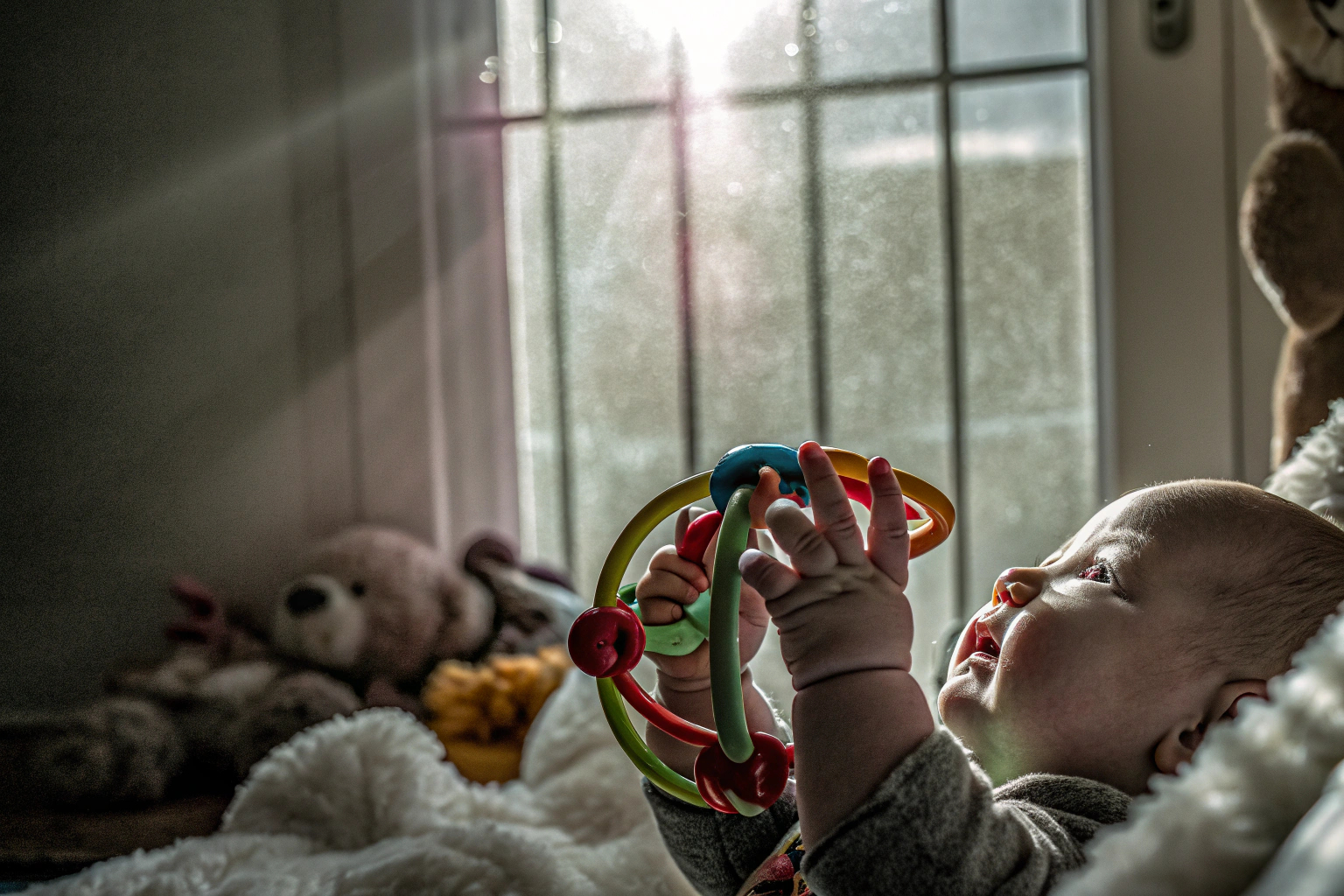 Detailaufnahme eines Babys, das mit einem bunten Spielzeug spielt, um seine Neugier zu wecken. Baby spielt mit buntem Spielzeug