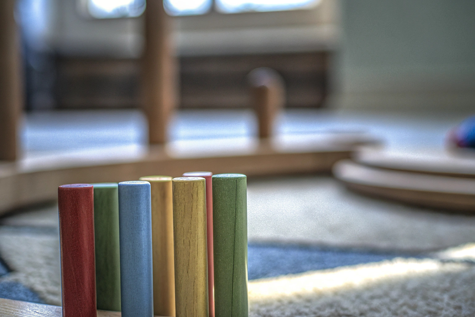 Detailaufnahme eines Kindes beim Spielen mit einem Montessori-Spielzeug, das aus bunten Holzstäbchen besteht. Montessori Spielzeug für Kinder