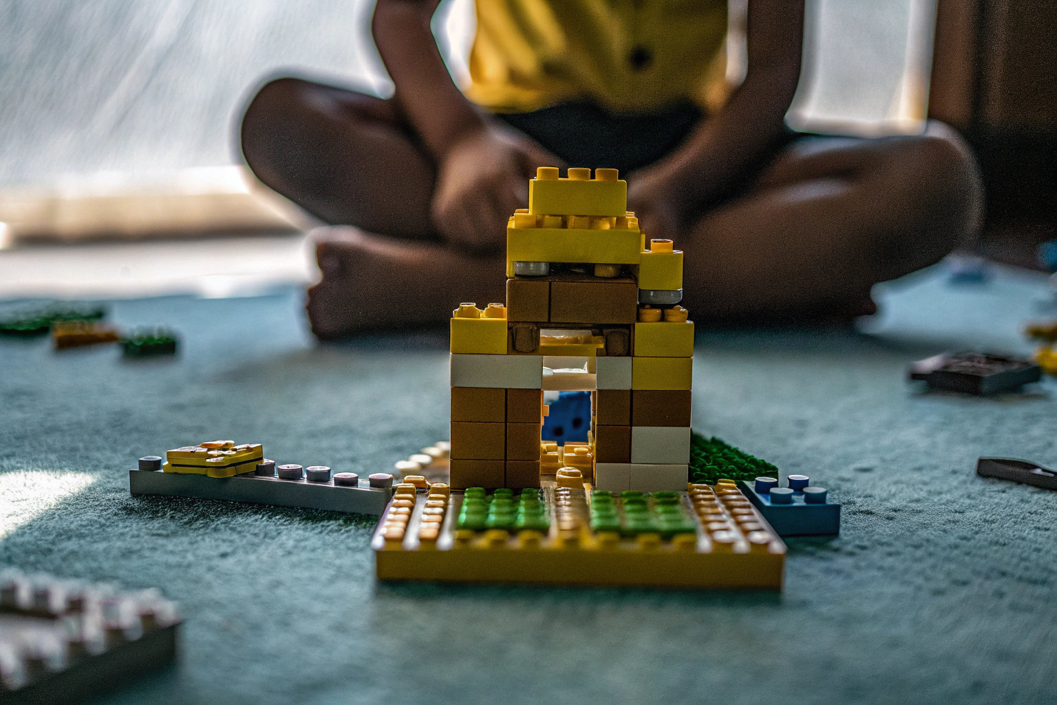 Ein Kind, das konzentriert an einem LEGO Disney Simba Set arbeitet, umgeben von verschiedenen LEGO-Steinen. Kind spielt mit LEGO Disney Simba Set
