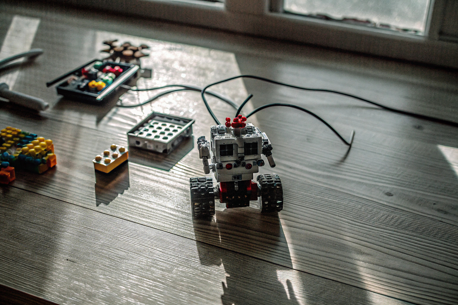 Ein Kind, das konzentriert an einem Lego Mindstorms Roboter arbeitet, umgeben von Bauklötzen und Teilen. Kind beim Bauen eines Lego Mindstorms Roboters