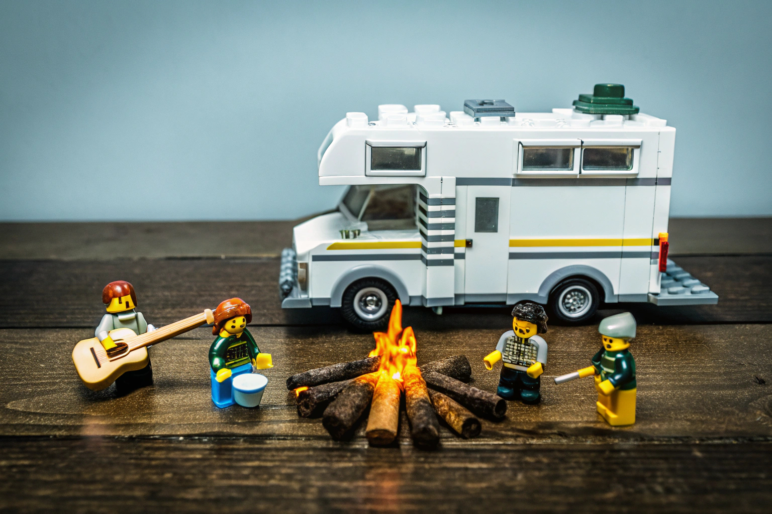 Ein LEGO City Abenteuer-Wohnmobil-Set aufgebaut auf einem Tisch mit Minifiguren, die das Lagerfeuer genießen. LEGO City Abenteuer-Wohnmobil Set mit Minifiguren