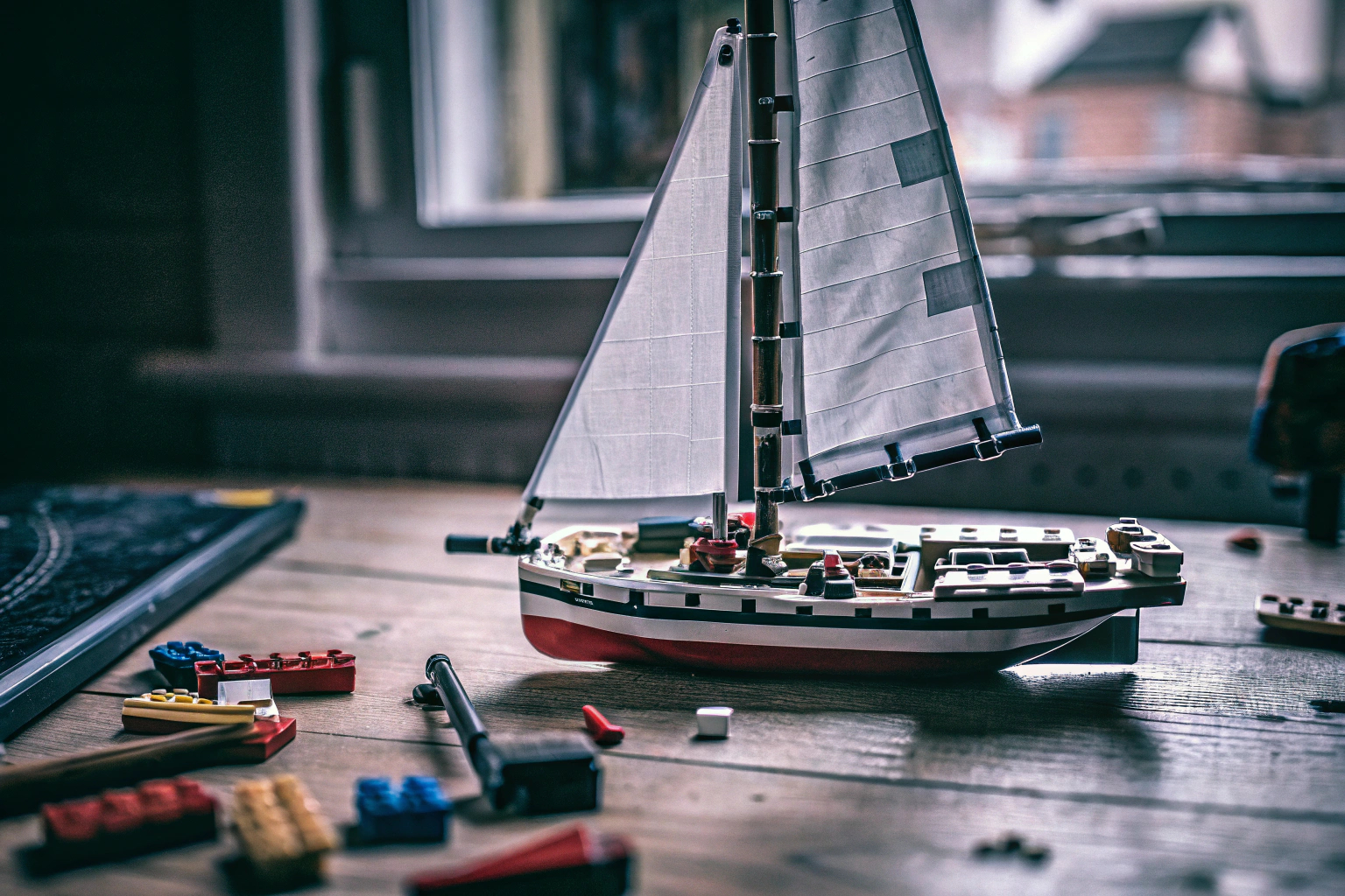Erwachsene, die gemeinsam an einem LEGO Technic Segelboot arbeiten, das auf einem Tisch ausgestellt ist. LEGO Technic Segelboot bauen