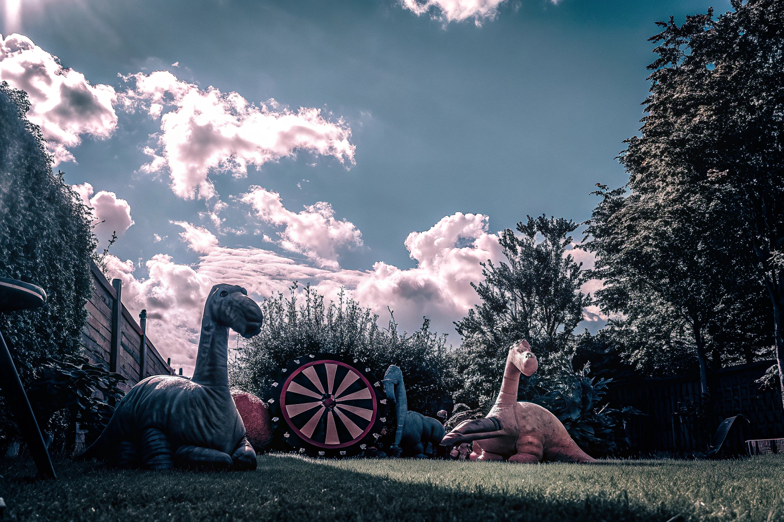 Kinder, die mit einer Dinosaurier-Dartscheibe im Garten spielen. Kinder spielen im Garten mit einer Dinosaurier-Dartscheibe