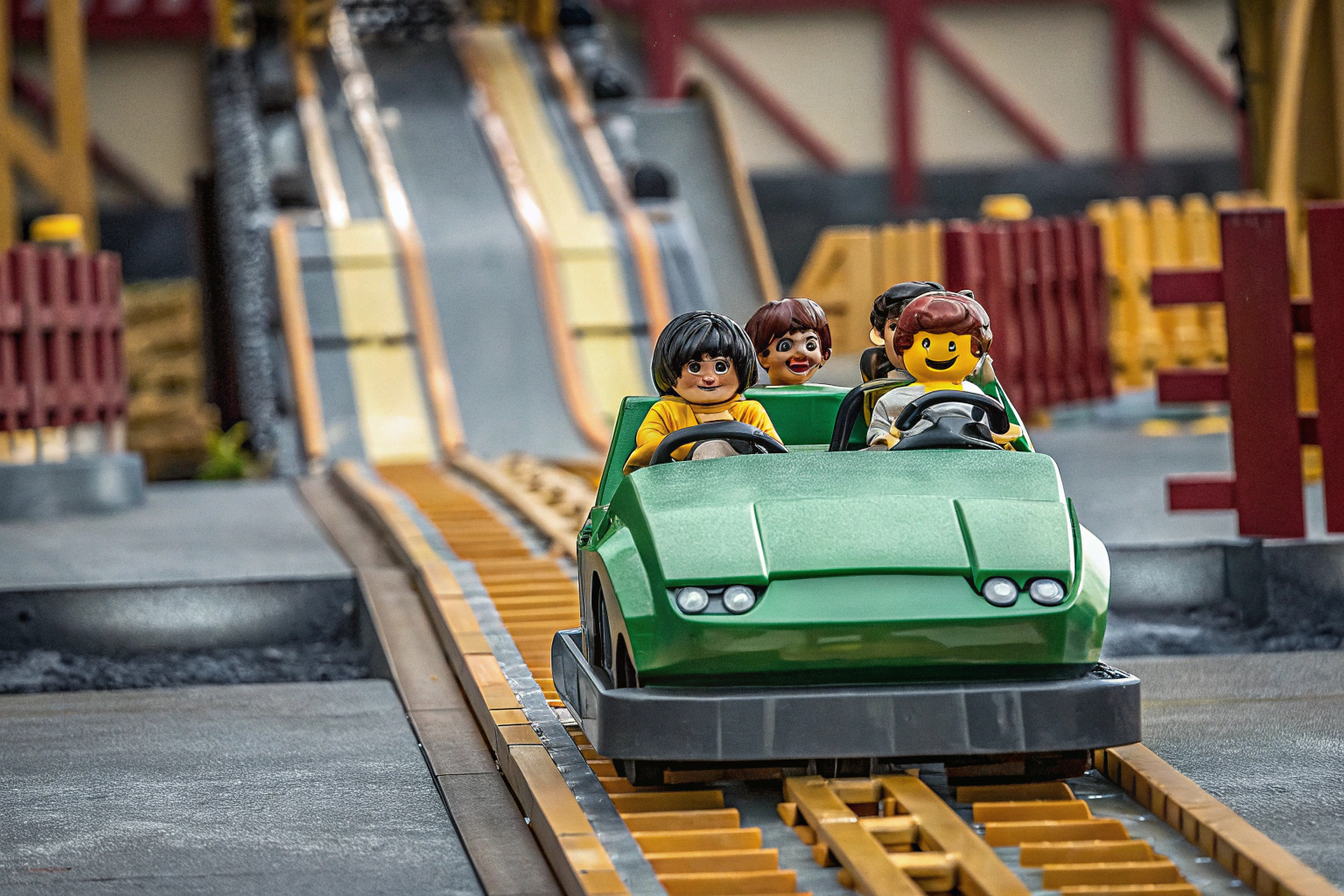 Lloyds Actionflitzer in voller Fahrt, mit den Minifiguren im Auto und einer Hindernisstrecke im Hintergrund. LEGO Ninjago Lloyds Actionflitzer im Spiel