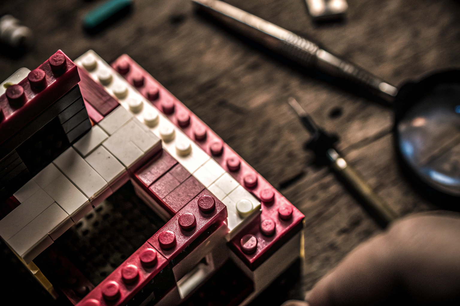 Nahaufnahme eines LEGO-Modells im Bau, mit verschiedenen Werkzeugen im Hintergrund. LEGO-Modell im Bau